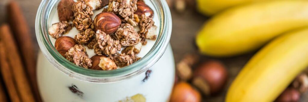 Słoiczek jogurtu z bananem i orzechami. Obrazek w artykule 4 pomysły na śniadanie dla cukrzyka, które są pyszne i bezpieczne
