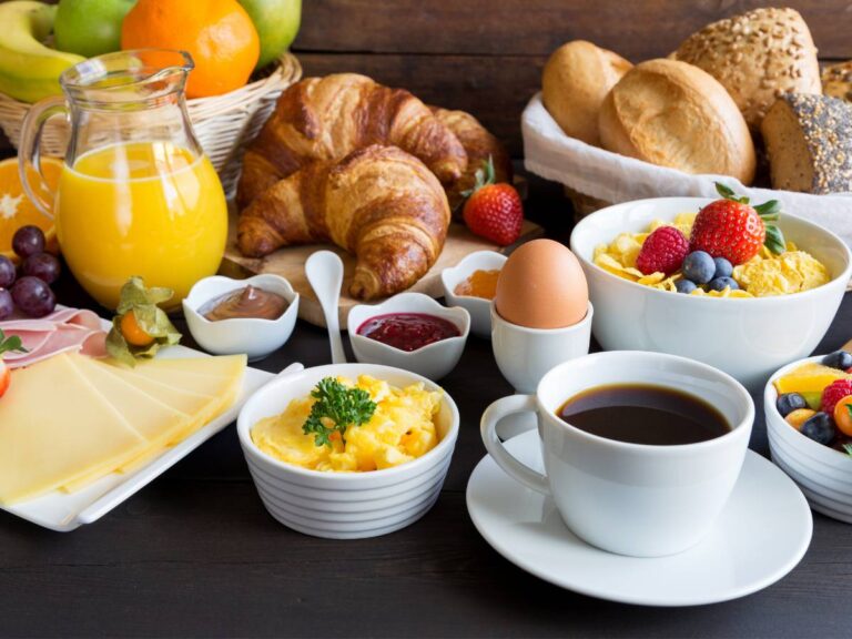 Stół ze śniadaniem z rogalikami, jajecznicą, kawa, sokami. Obrazek w artykule Najlepsze 10 przepisów na zdrowe śniadanie, jeśli zdrowie jest Twoim priorytetem