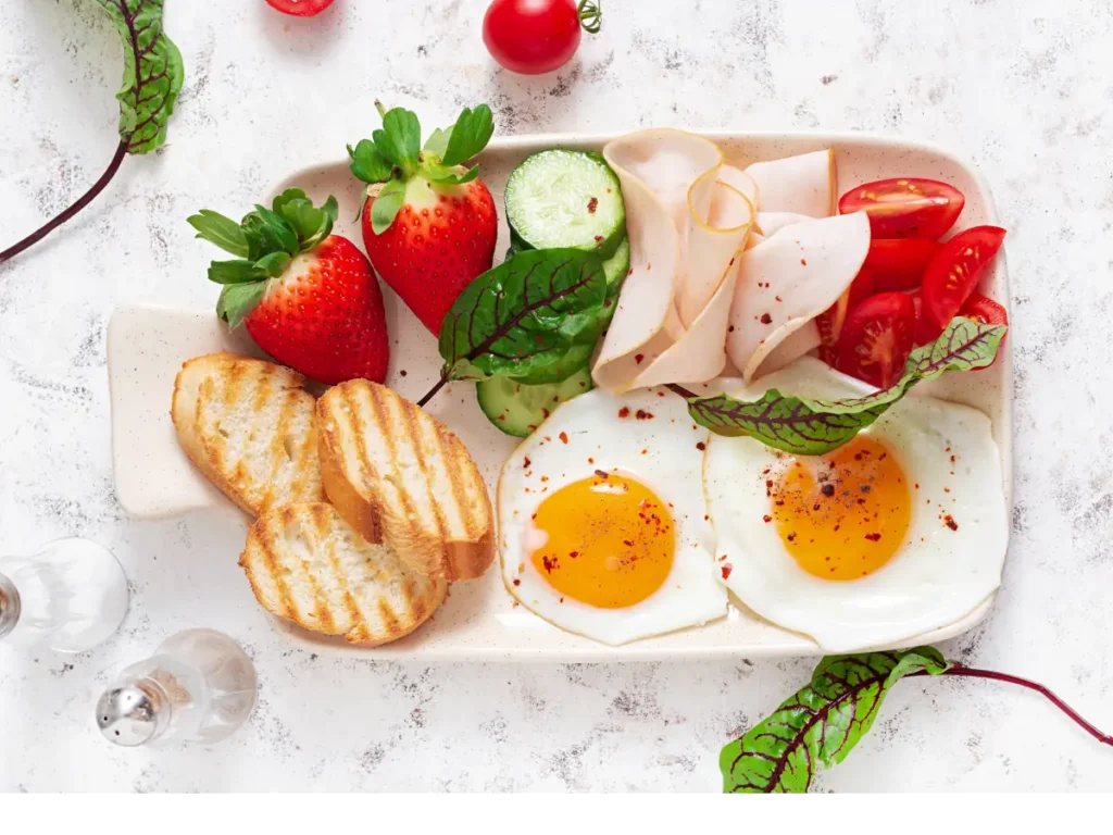 Talerz z jajkami sadzonymi i warzywami. Obrazek w artykule 5 przepisów na lekkie śniadanie do 300 kcal, które nie obciąży Twojej diety