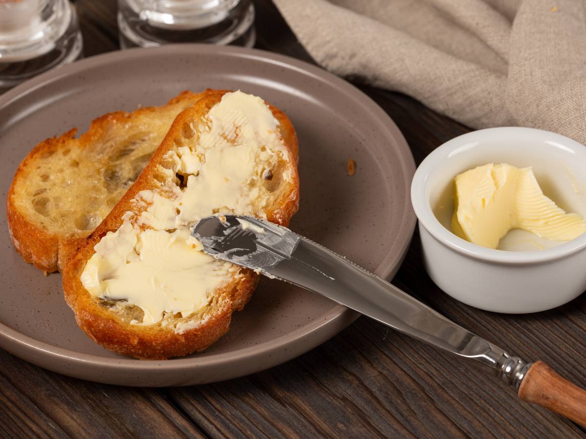 Talerz z omletem i nóż i masło obok. Obrazek w artykule Doradzamy, co zamiast chleba na śniadanie, jeśli szukasz urozmaicenia