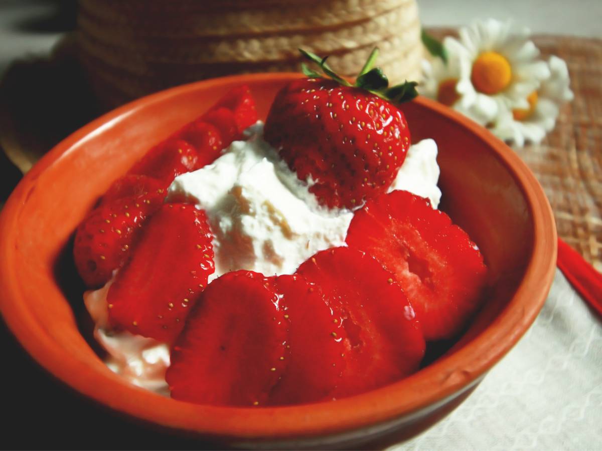 Miseczka z serkiem wiejskim i truskawkami. Obrazek w artykule TOP 4 sposoby na fit śniadanie z serkiem wiejskim, które nie dostarczają nadmiaru kalorii
