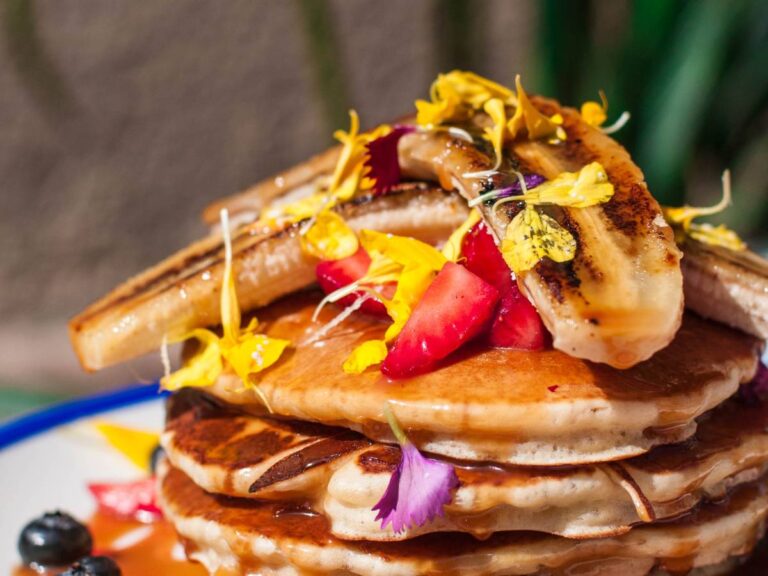 Talerz naleśników jeden na drugim z owocami. Obrazek w artykule 5 pysznych przepisów na pancakes na śniadanie, które osłodzą Twój poranek