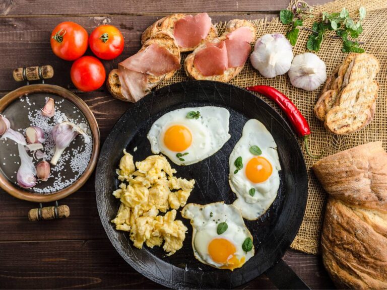Talerze z jajkami sadzonymi, jajecznica, wedlinami i pomidorami. Obrazek w artykule 5 przepisów na pyszne proteinowe śniadanie, które zbuduje Twoje mięśnie