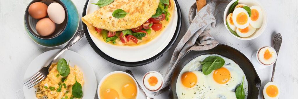 Talerze z omletem, jajkami sadzonymi i dekoracje z owoców. Obrazek w artykule 5 przepisów na pyszne proteinowe śniadanie, które zbuduje Twoje mięśnie