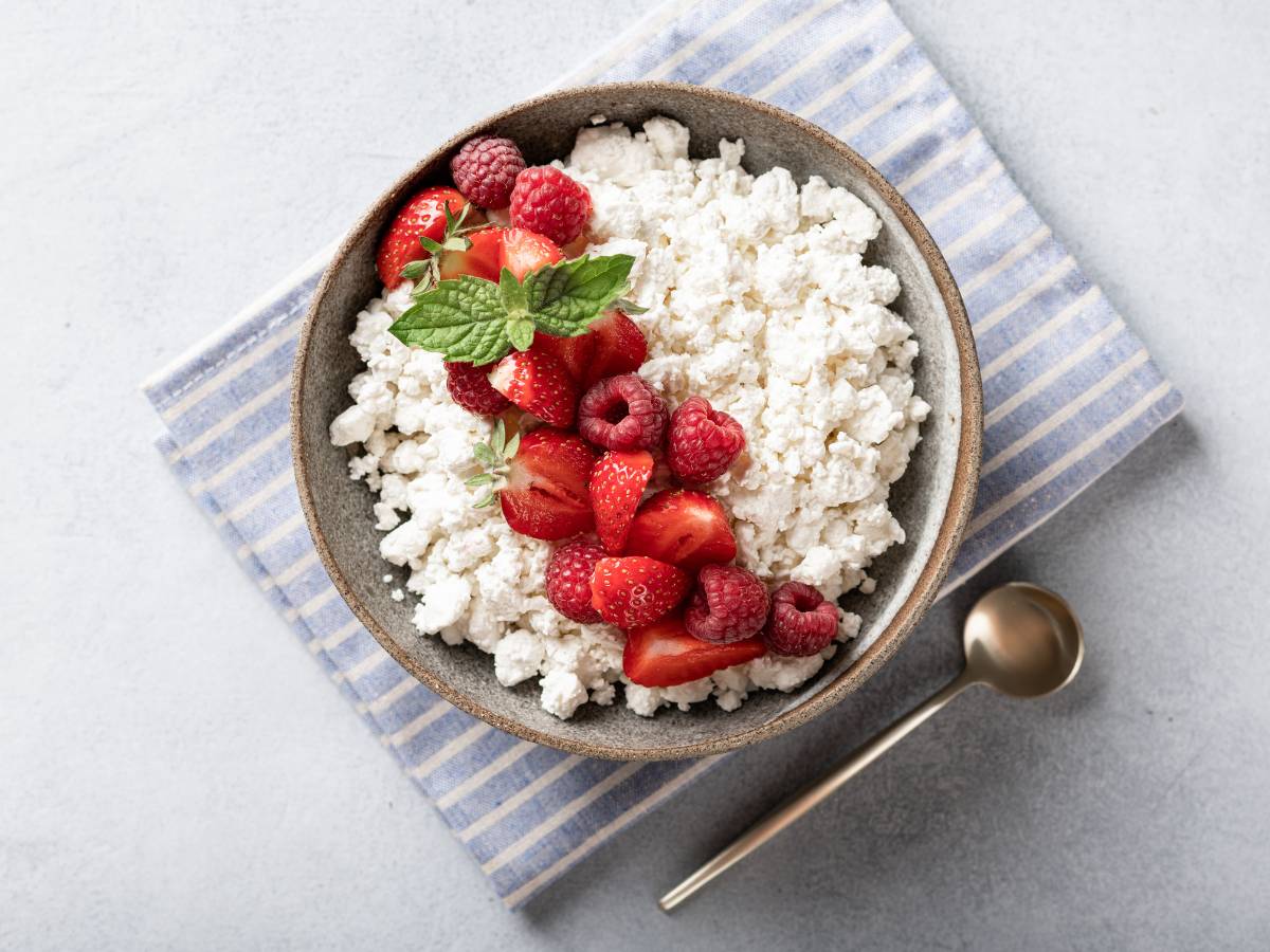 Miseczka z twarożkiem i malinami na wierzchu. Obrazek w artykule Genialne 4 sposoby na serek wiejski na śniadanie, które sprawią, że pokochasz ten produkt