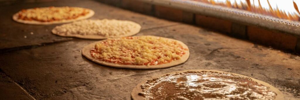 Stół z plackami pizzy. Obrazek w artykule Śniadanie z piekarnika, które zaskoczy Cię swoim niepowtarzalnym smakiem