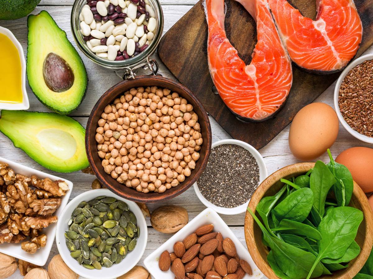 Blat z produktami wysokobiałkowymi: awokado, łosoś, szpinak, ciecierzyca. Obrazek w artykule 5 przepisów na sycące śniadanie białkowo tłuszczowe bez jajek, dla tych, którzy ich unikają