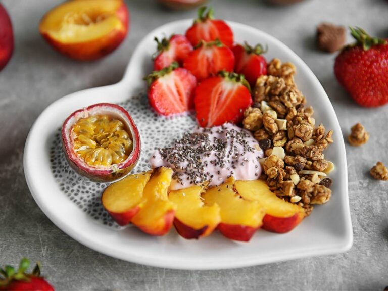 Talerz w kształcie serca z jaogurtem z chia i krojonymi truskawkami, figą, mango. Obrazek w artykule 5 przepisów na zdrowe śniadanie z nasionami chia, które dostarczy Ci mnóstwa wartości odżywczych