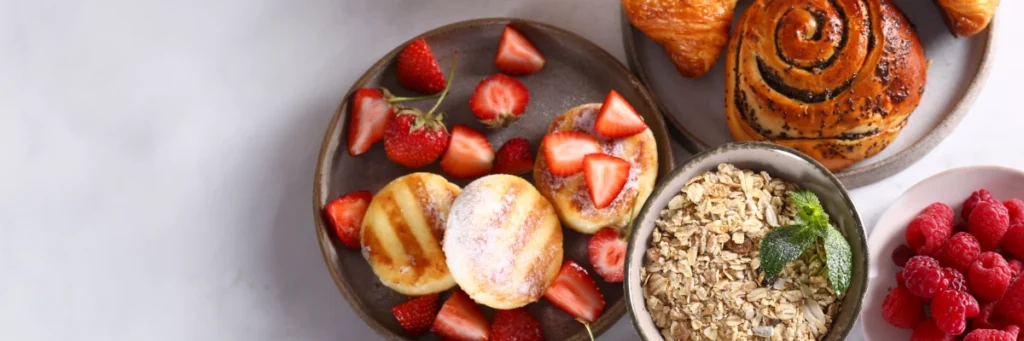 Talerz ze sniadaniem z miseczki owsianki, jogurtu i dodatków. Obrazek w artykule 4 inspiracje na to, co zrobić na śniadanie, gdy brakuje Ci pomysłu