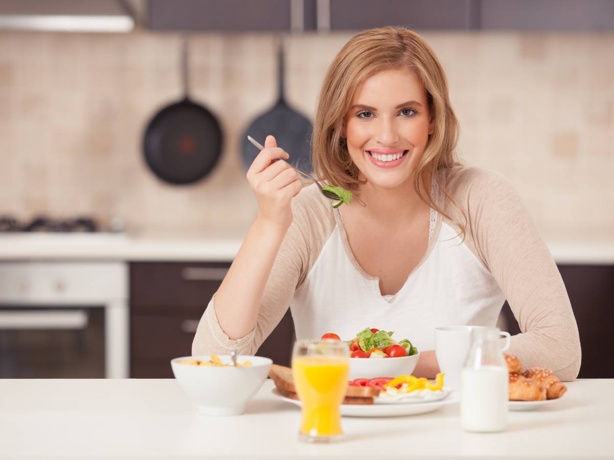 Kobieta siedzi przy stole ze śniadaniem. Obrazek w artykule Odkryj najlepsze pomysły na pożywne i sycące śniadanie, idealne, gdy jesteś głodny