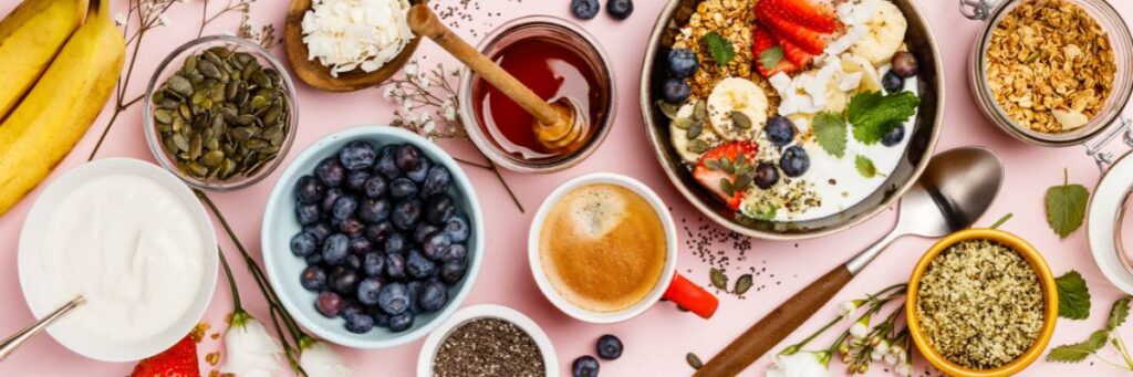 Stół zastawiony miseczkami z owocami, dodatkami i talerzem ze sniadaniem z jajkami.  Obrazek w artykule 5 patentów na pyszne śniadanie, od którego nie przytyjesz