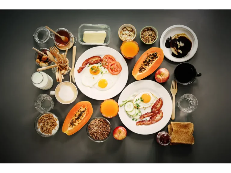 Stół zastawiony miseczkami i talerzykami z jedzeniem, kubek z kawą i owoce. Obrazek w artykule TOP 4 przepisy na śniadanie 500 kcal, które sprawią, że poranne wstawanie stanie się przyjemnością