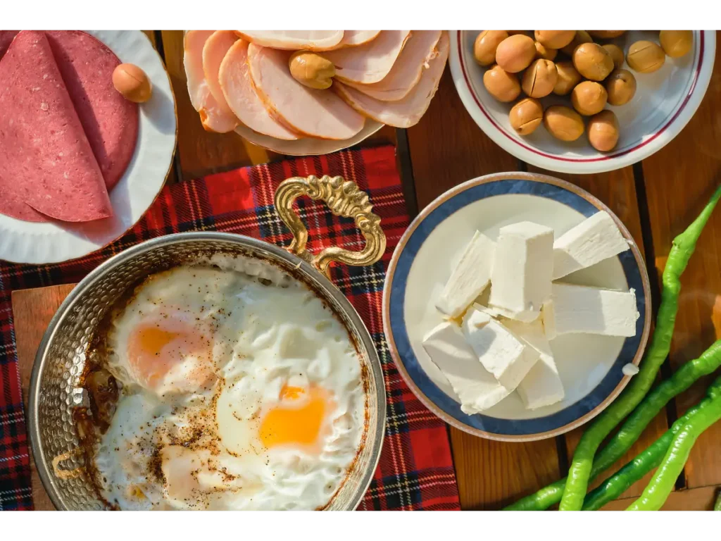 Jajka sadzone na talerzu, twaróg i inne produkty na śniadanie. Obrazek w artykule Sprawdzone 4 przepisy na śniadanie na kaca, które naprawdę działają