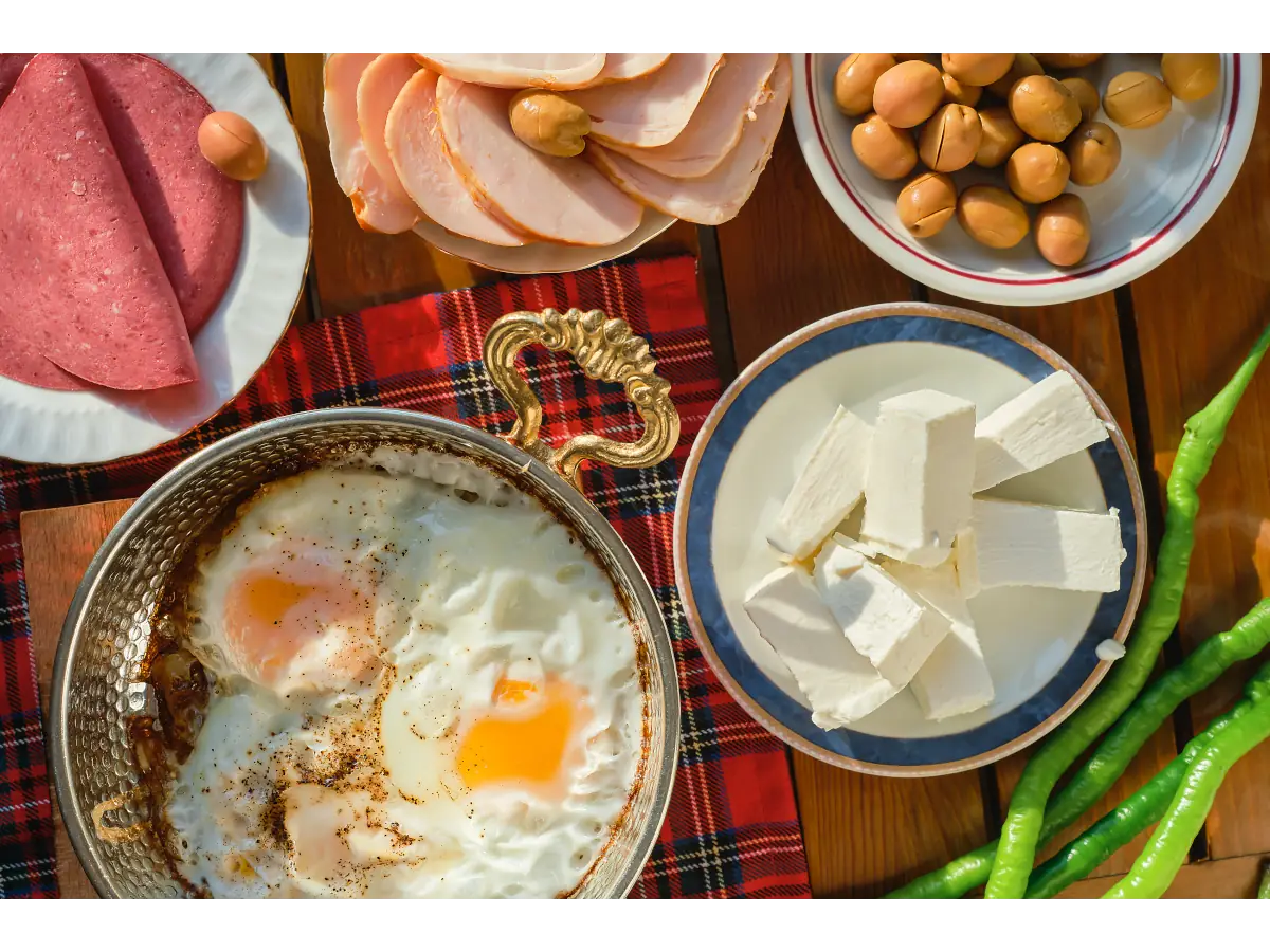 Jajka sadzone na talerzu, twaróg i inne produkty na śniadanie. Obrazek w artykule Sprawdzone 4 przepisy na śniadanie na kaca, które naprawdę działają