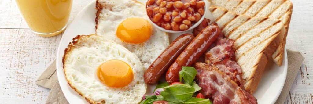 Jajka, kiełbaski, fasolka na talerzu. Obrazek w artykule Przepis na najlepsze śniadanie po angielsku - poczuj się jak w Londynie