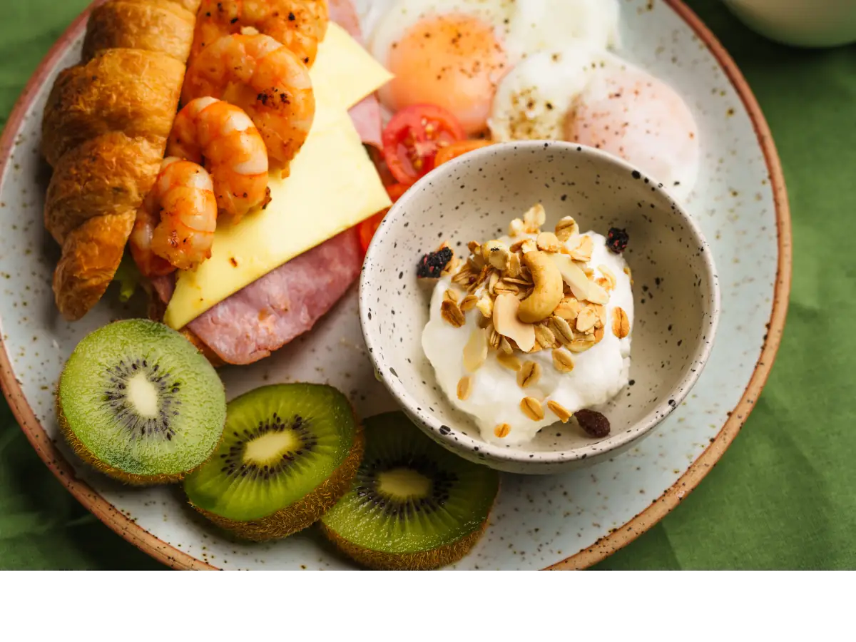 Miseczka z owsianka z orzechami, pokrojone kiwi i rogaliki. Obrazek w artykule 5 pomysłów na szybkie śniadanie dla zabieganych