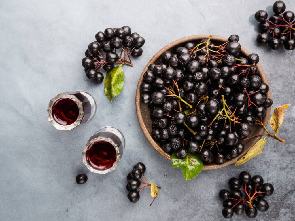 Miseczka owoców aronii i kieliszki z sokiem.