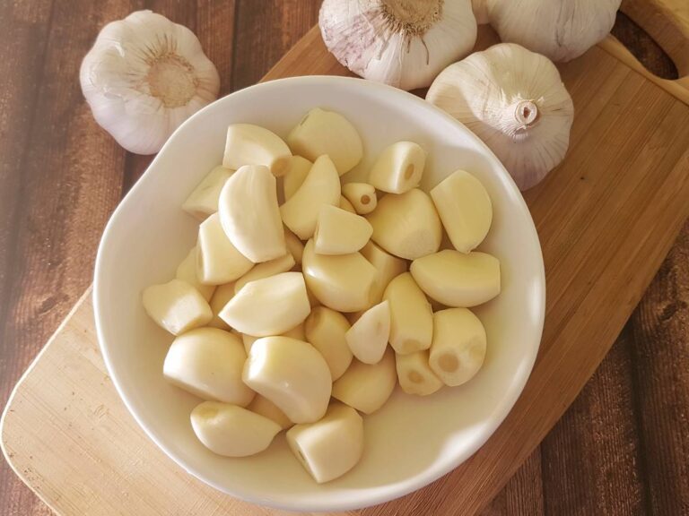 Biała miseczka z obranymi ząbkami czosnku.
