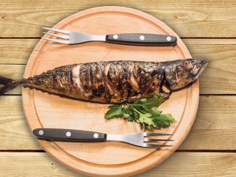 Pieczona makrela podana na drewnianej desce.