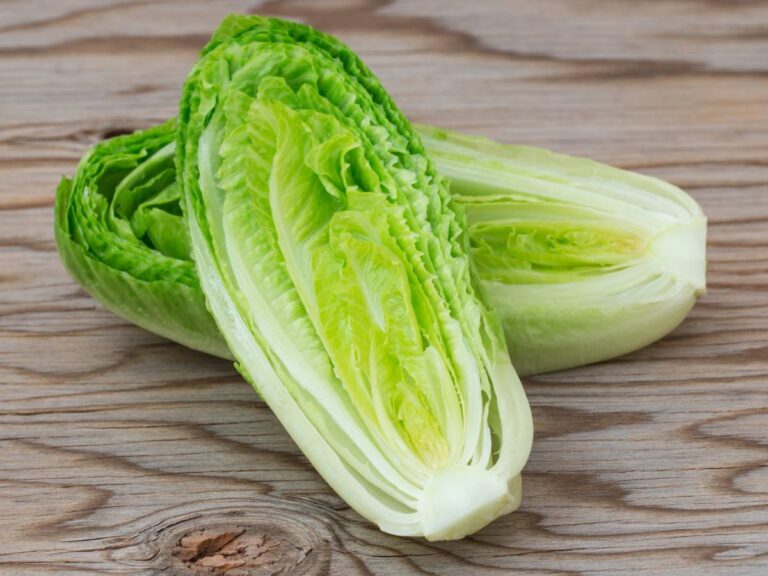 Dwie główki sałaty rzymskiej na drewnianym blacie.